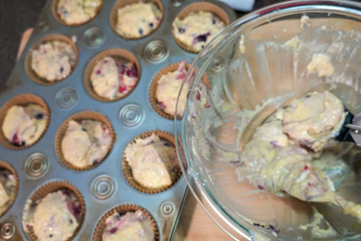 scooped batter in baking cups in a muffin pan with leftover batter in a bowl.