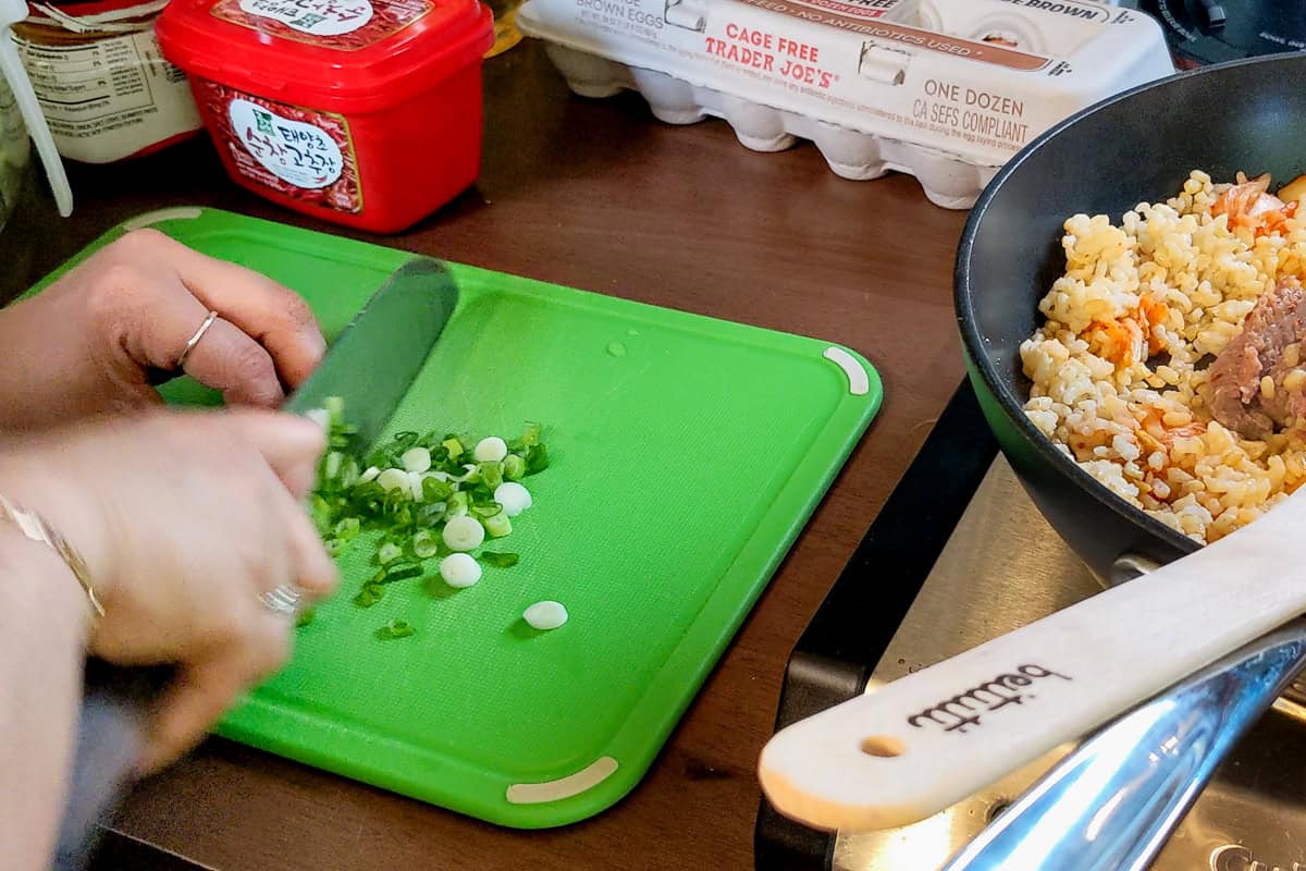 chopping scallions on a cutting board.