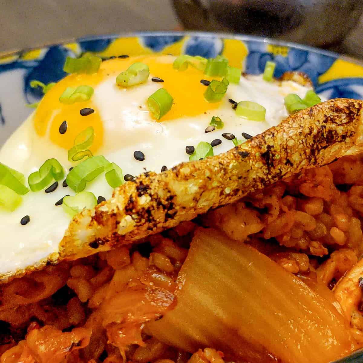 close up of garnished fried crispy egg on kimchi rice.
