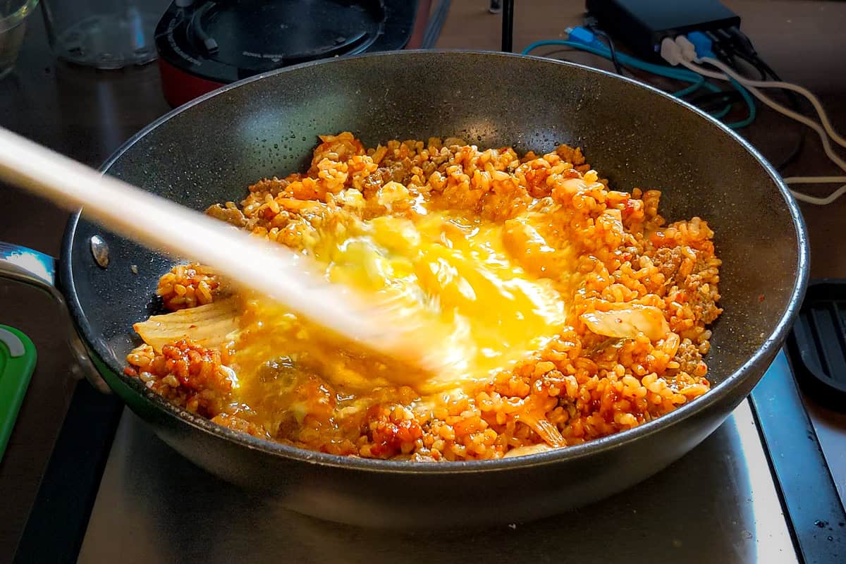 spatula scrambling eggs in a pan with a wooden spatula.