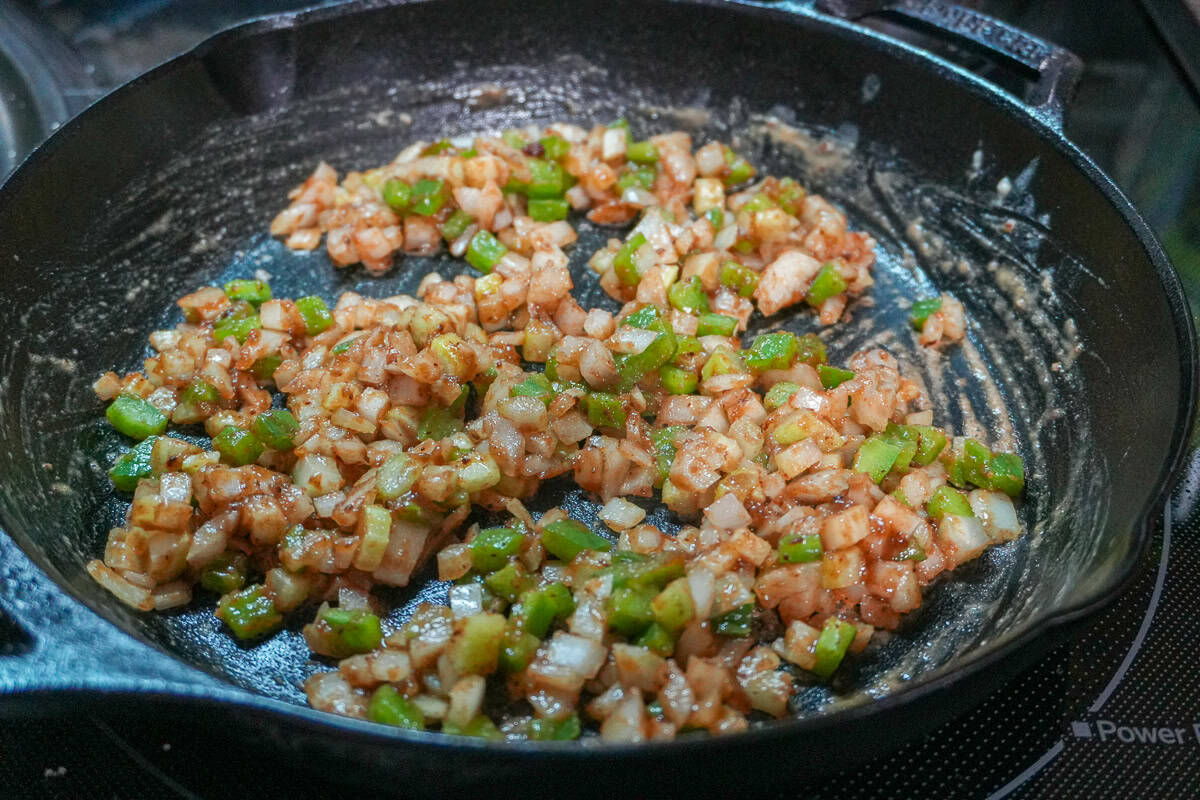 holy trinity (green bell pepper, onion and celery) sweating in a cast iron pan with the roux.