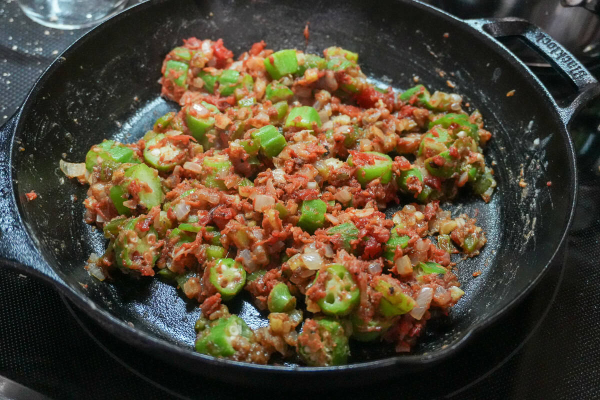 tomato sauce added to the roux, holy trinity and okra mixture in a skillet.