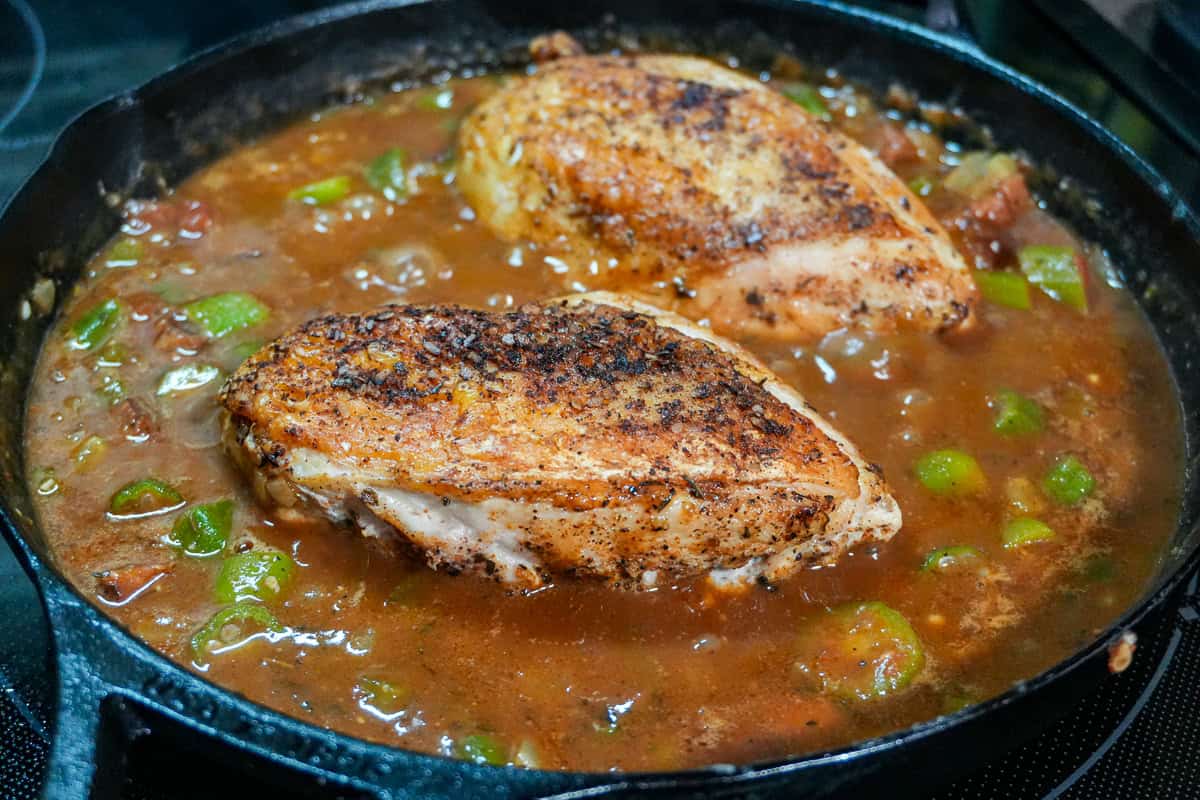 seared skin on chicken breast on top of the gumbo in a lodge cast iron pan.