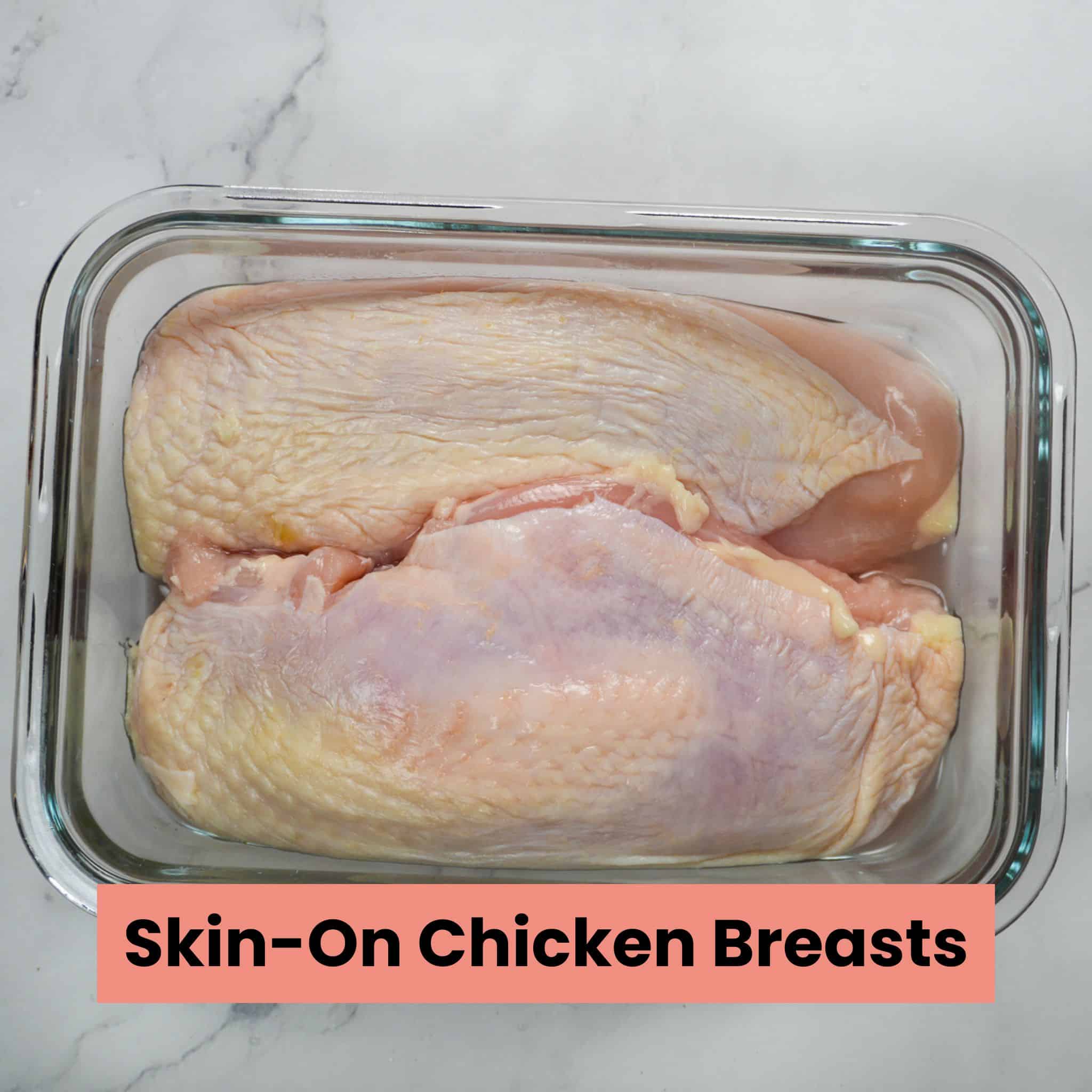 skin on chicken breast in a rectangle glass container.