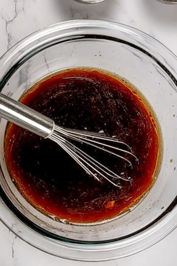 the finished Spicy Sesame Soy Dressing in a glass bowl with a mini whisk