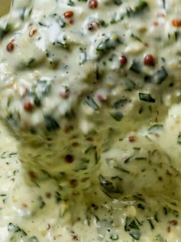 close up of the Lemon Dijon Mustard Remoulade on a spoon dripping back into a container.