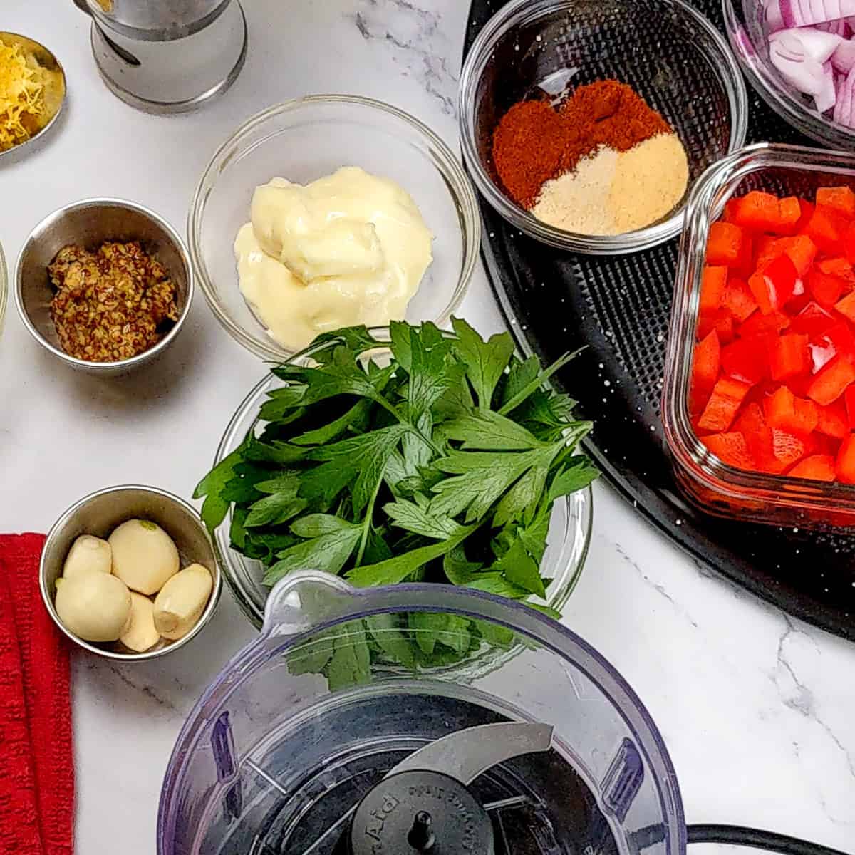 Ingredients for the Lemon Dijon Mustard Remoulade spread out next to the kitchenaid food chopper.