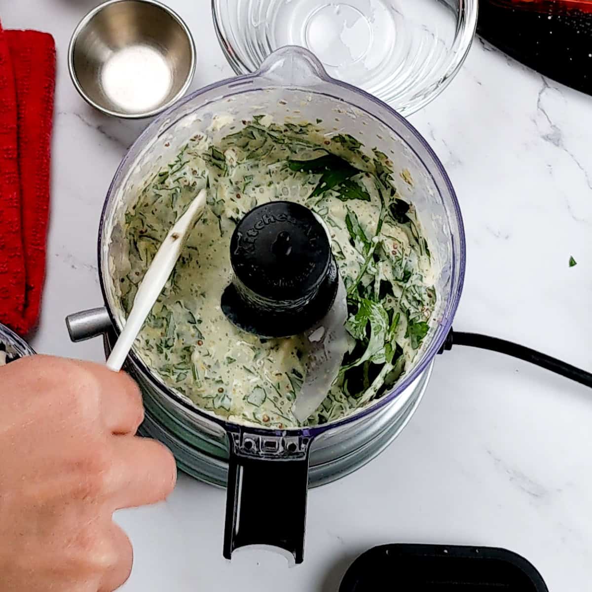 small spatula used to scrape the sides of the food chopper.