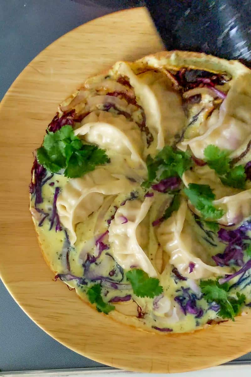 finished potsticker dish being slide onto wide flat plate from non-stick pan.