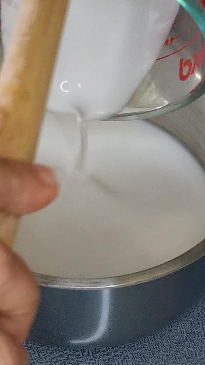 pouring coconut milk into a small saucepan.