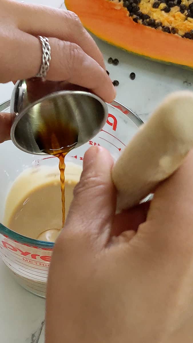 vanilla and rum extract added to the cream mixture in a measuring cup.