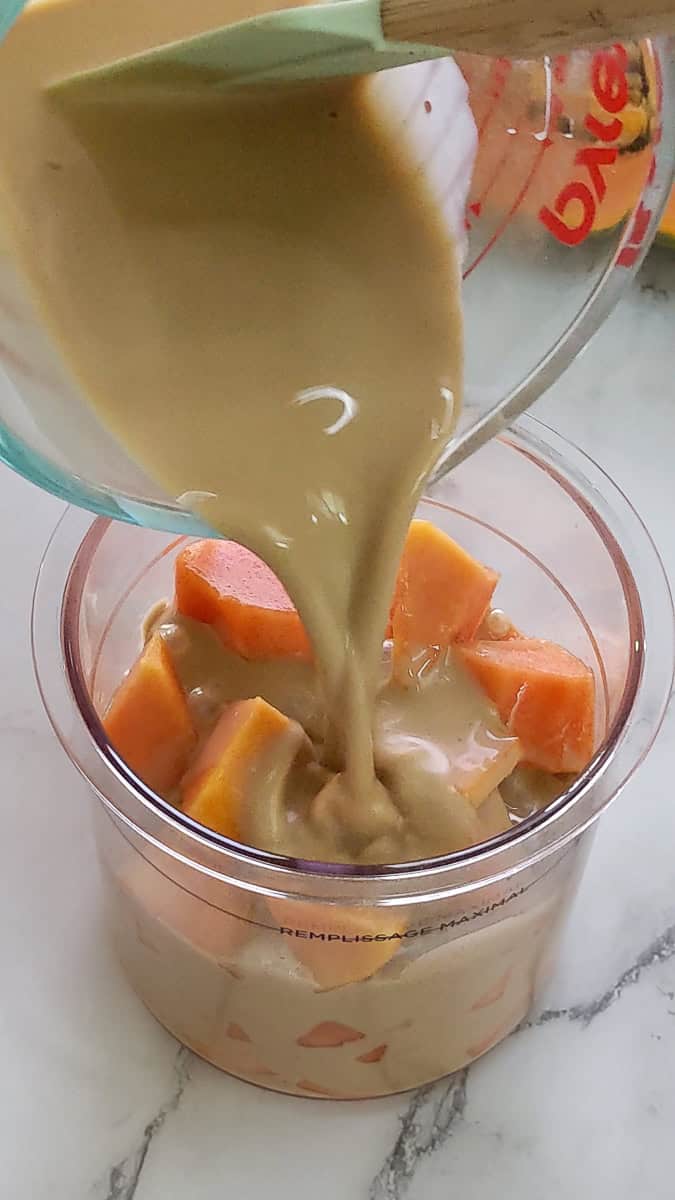pouirng the warm coconut rum cream over the papaya chunks.