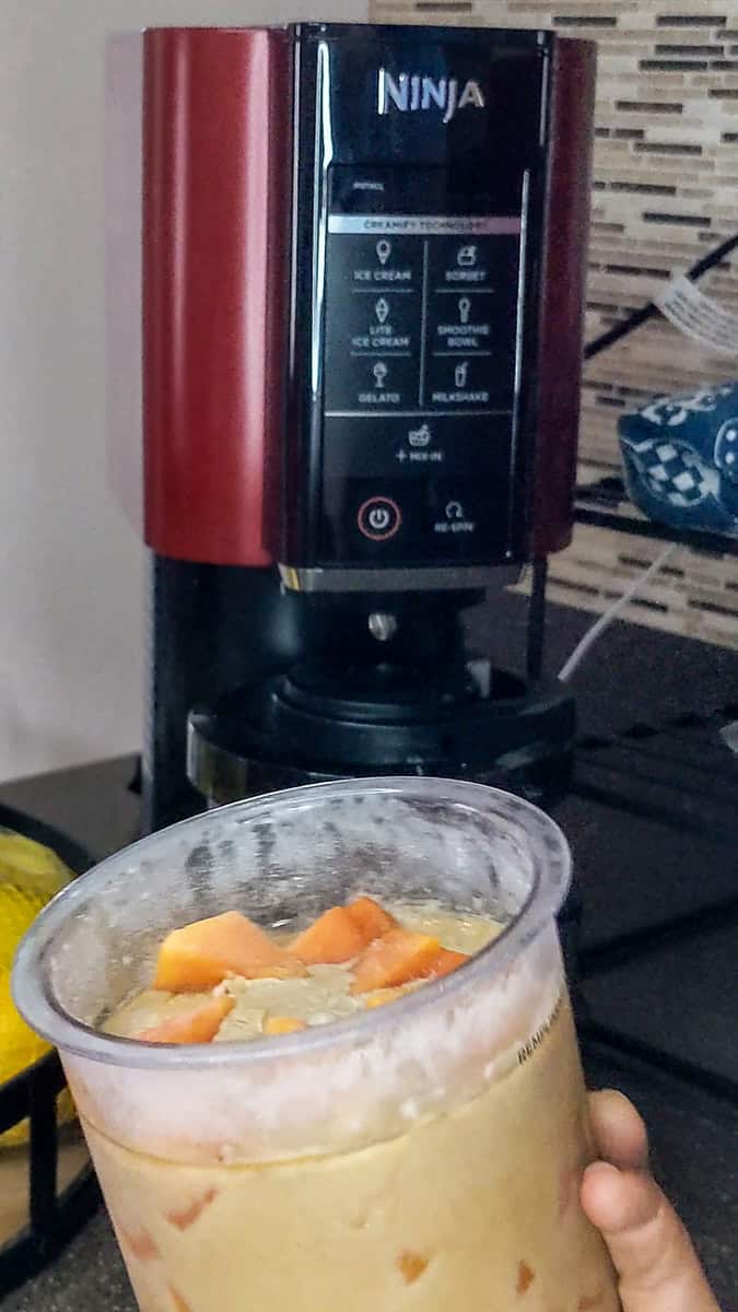 showing the frozen papaya coconut rum mixture in the ninja creami pint container.