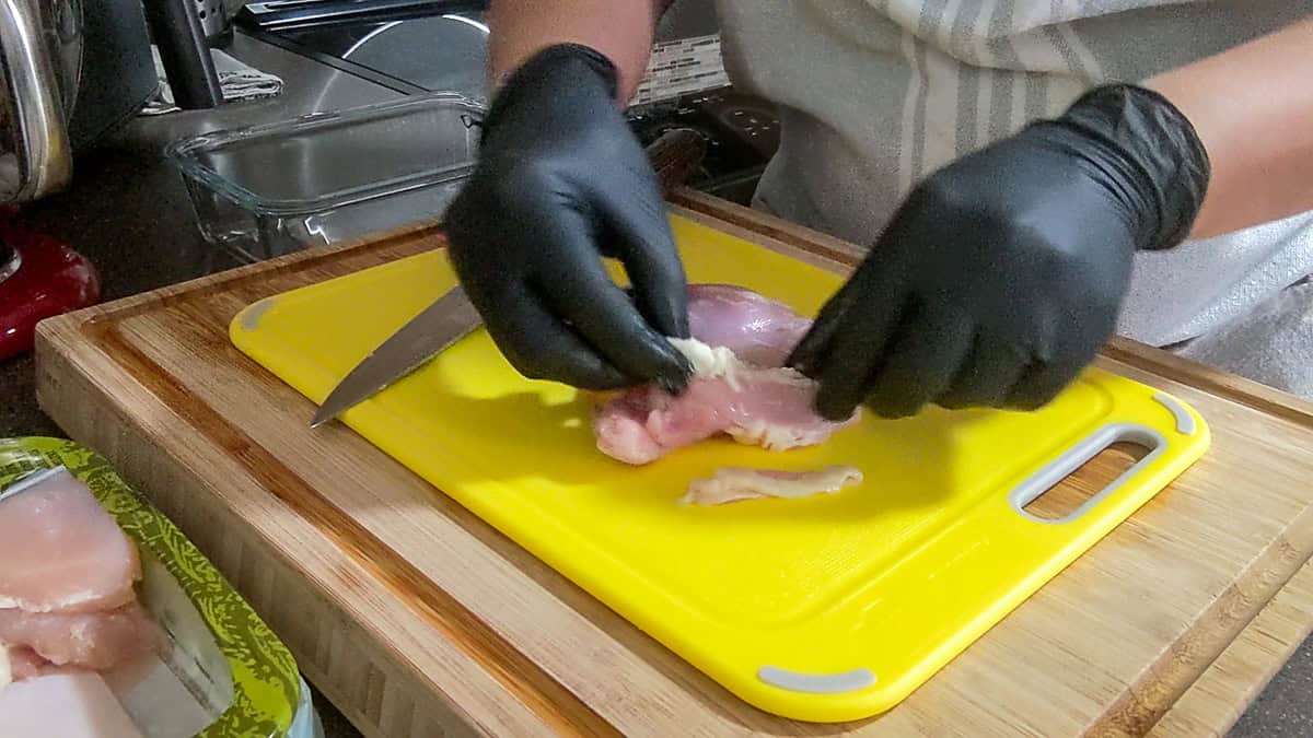 using fingers to pull up fat on chicken thigh.