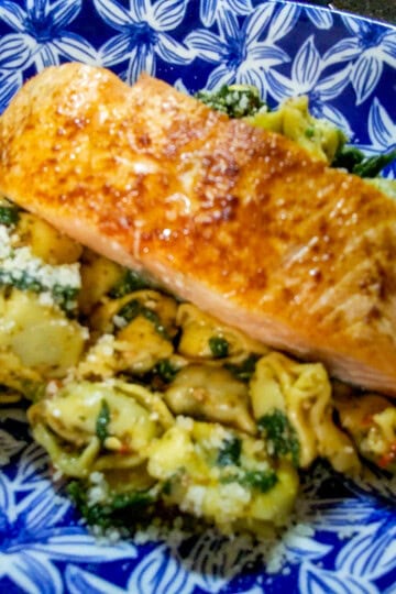 Delicious baked salmon served with tortellini pasta and spinach.