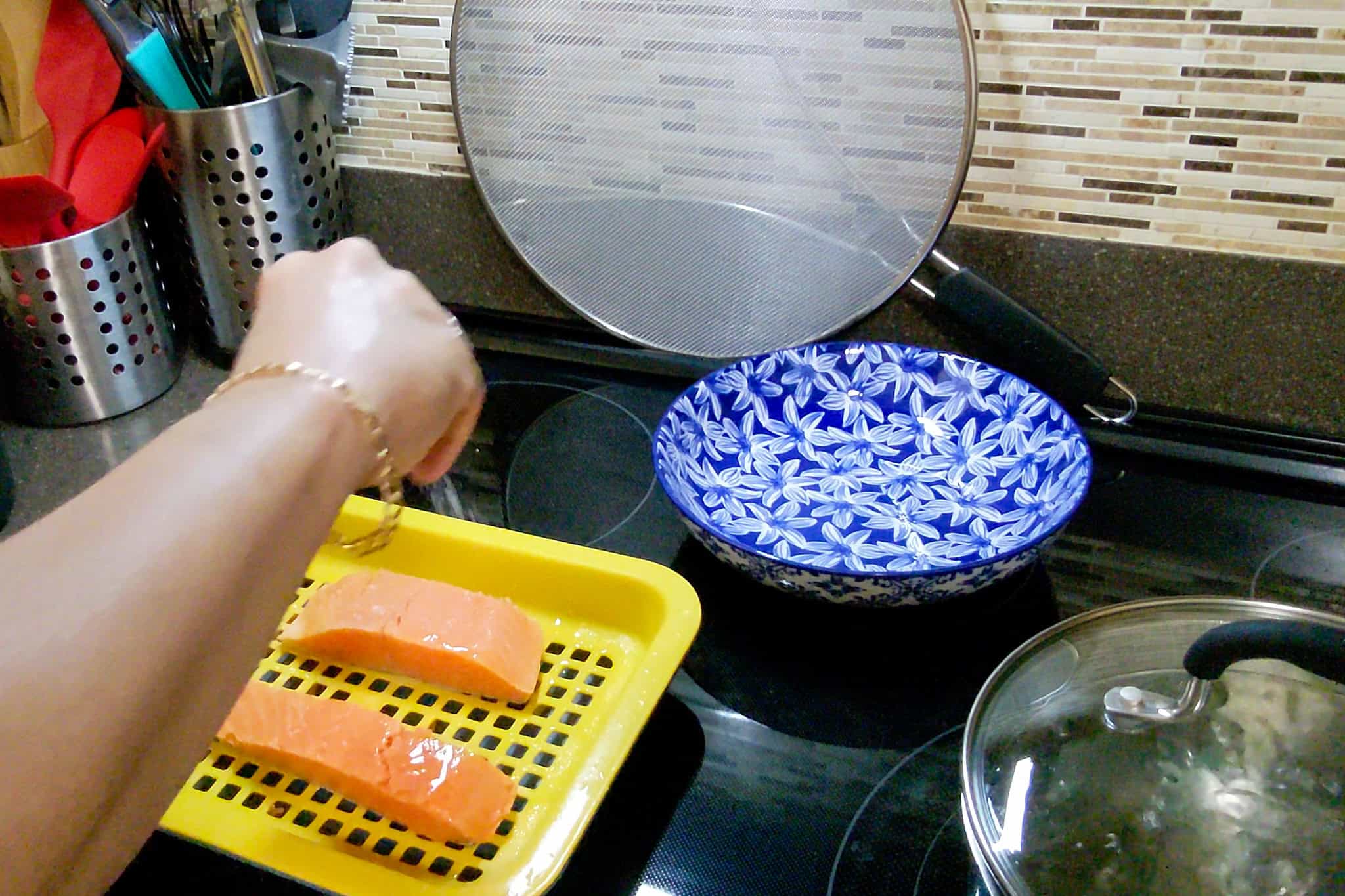 Chef Maika preparing salmon fillets on a yellow tray in a kitchen.
