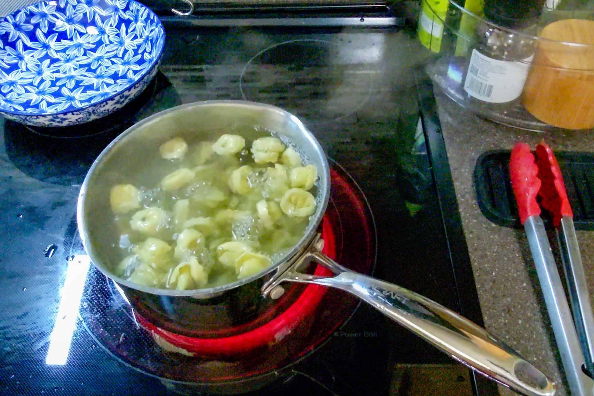 Tortellini boiling in a pot on a stove for cooking.