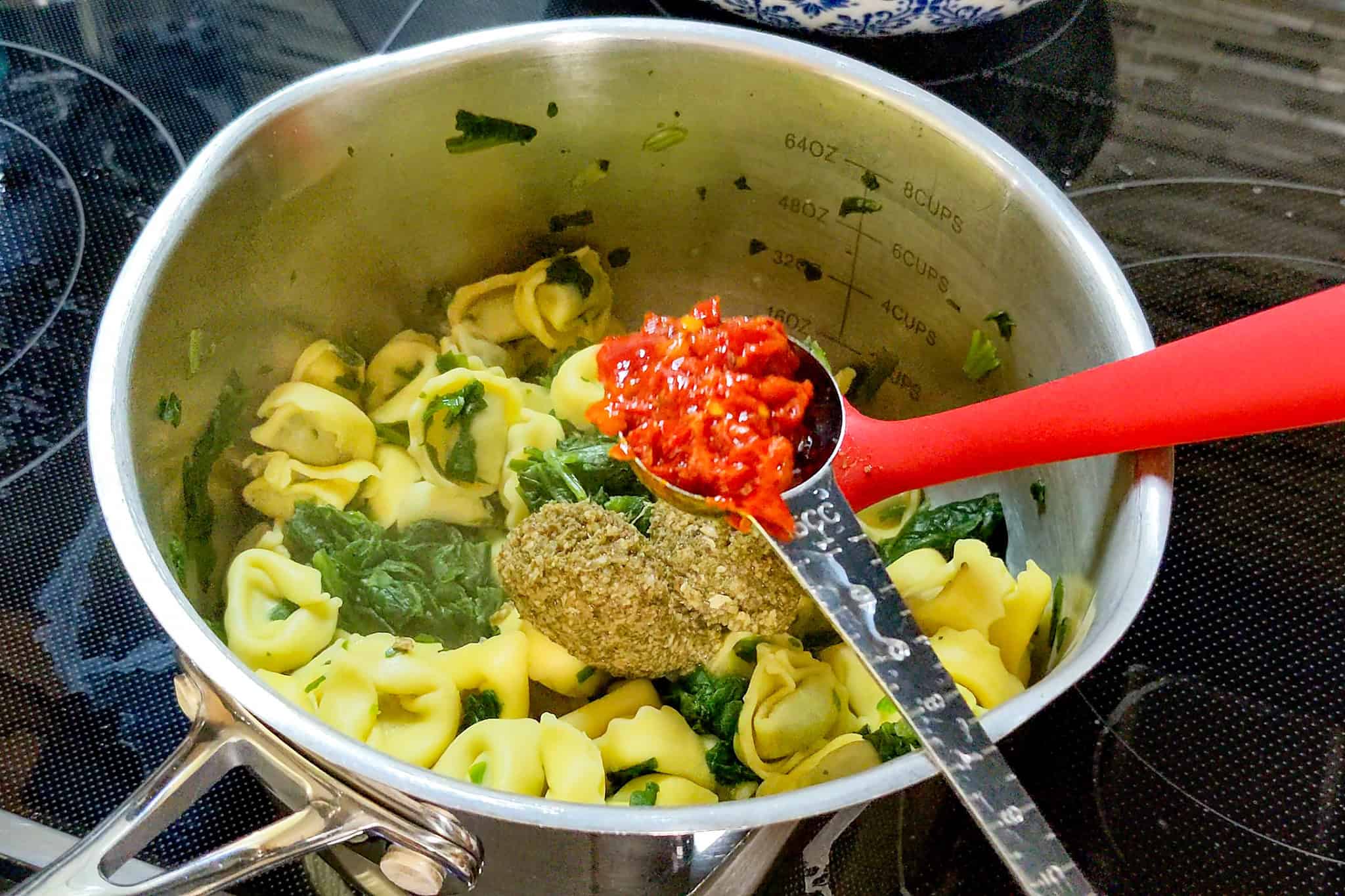 Tortellini pasta with spinach and bomba sauce in a pot for cooking.