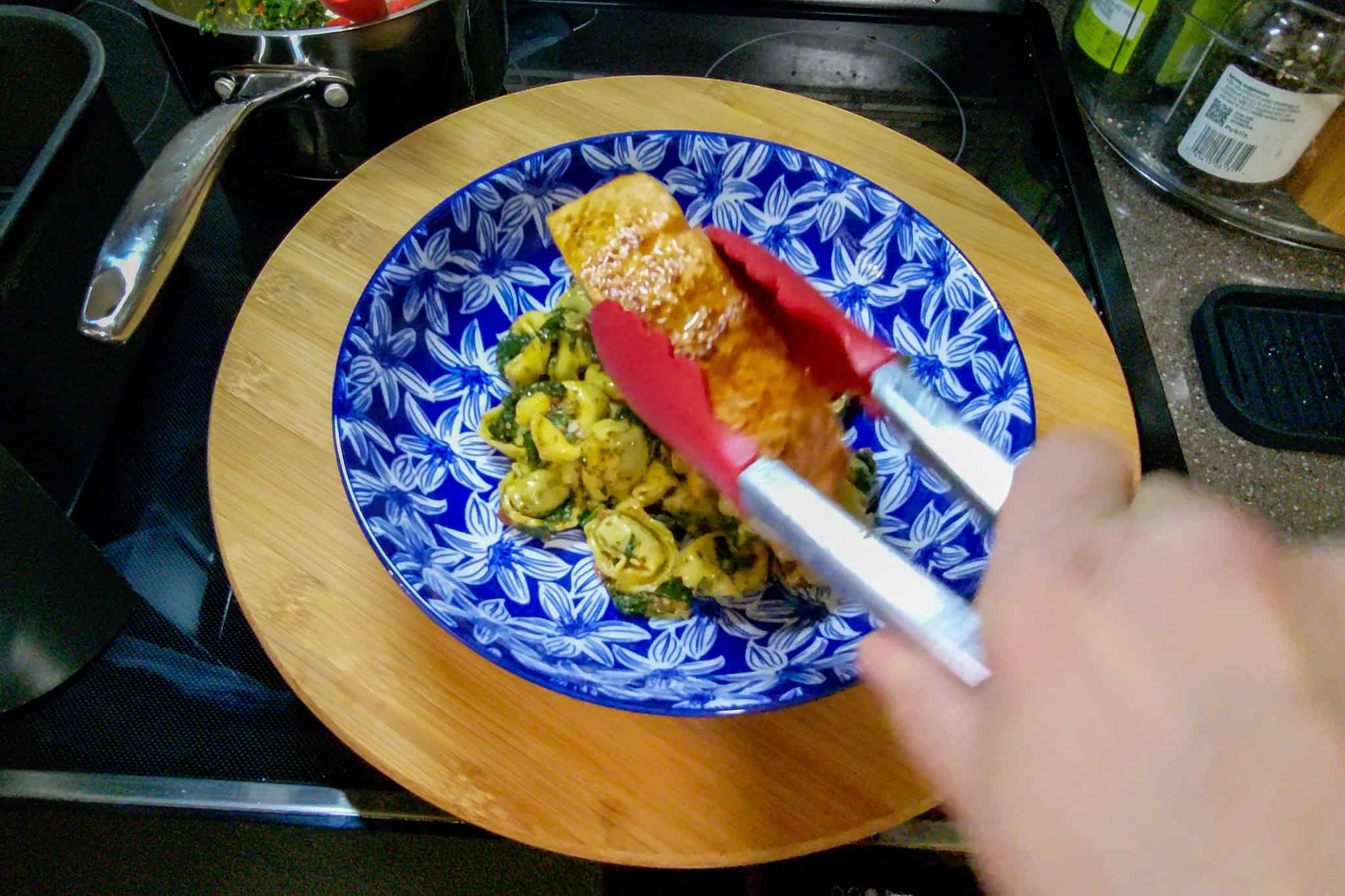 Preparing homemade pasta with vegetables in a blue patterned bowl.