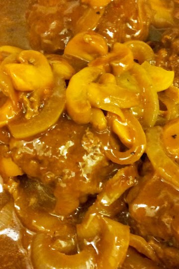 Close-up of Salisbury steak with mushroom gravy and sliced mushrooms.