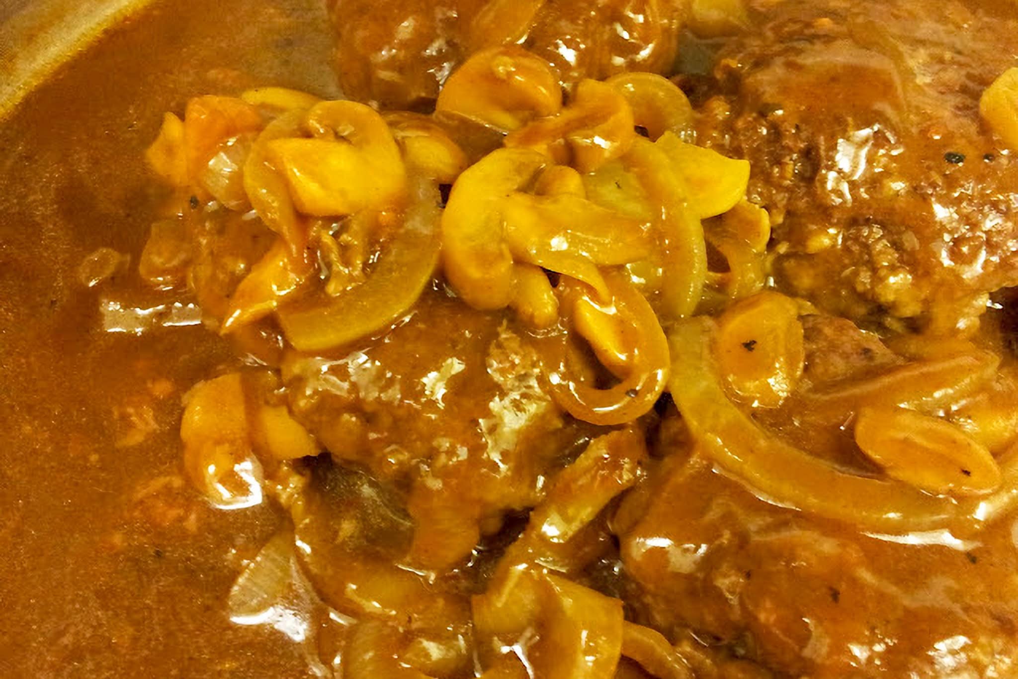 Close-up of Salisbury steak with mushroom gravy and sliced mushrooms.