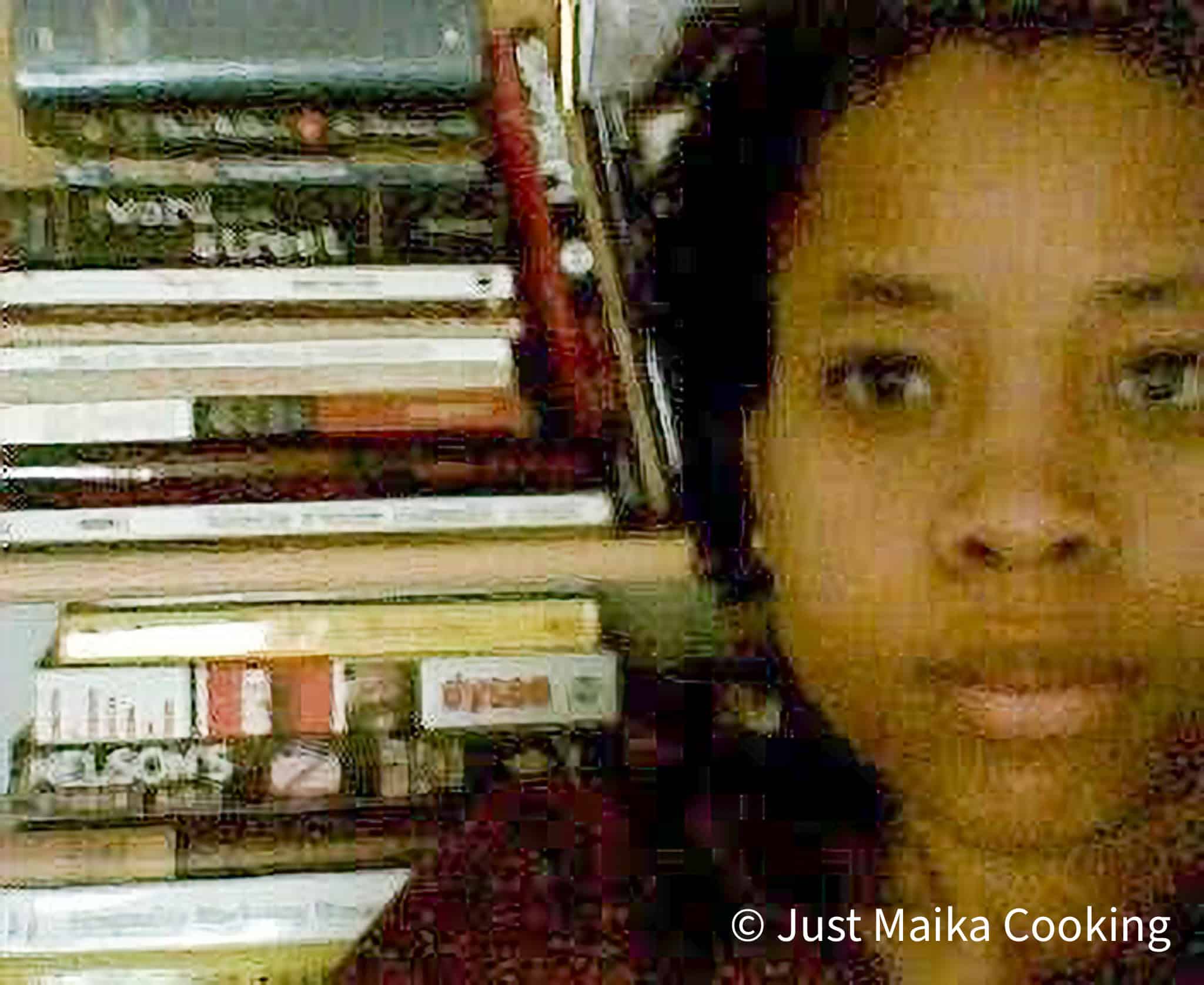a low quality photo of chef maika with her first digital camera staring forward in front of her bookshlf.