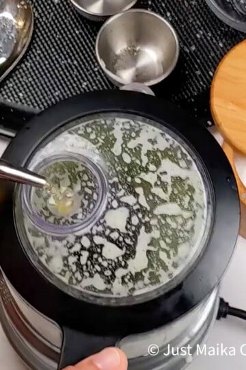 Blender blending cilantro, jalapeños, and lime for sauce.