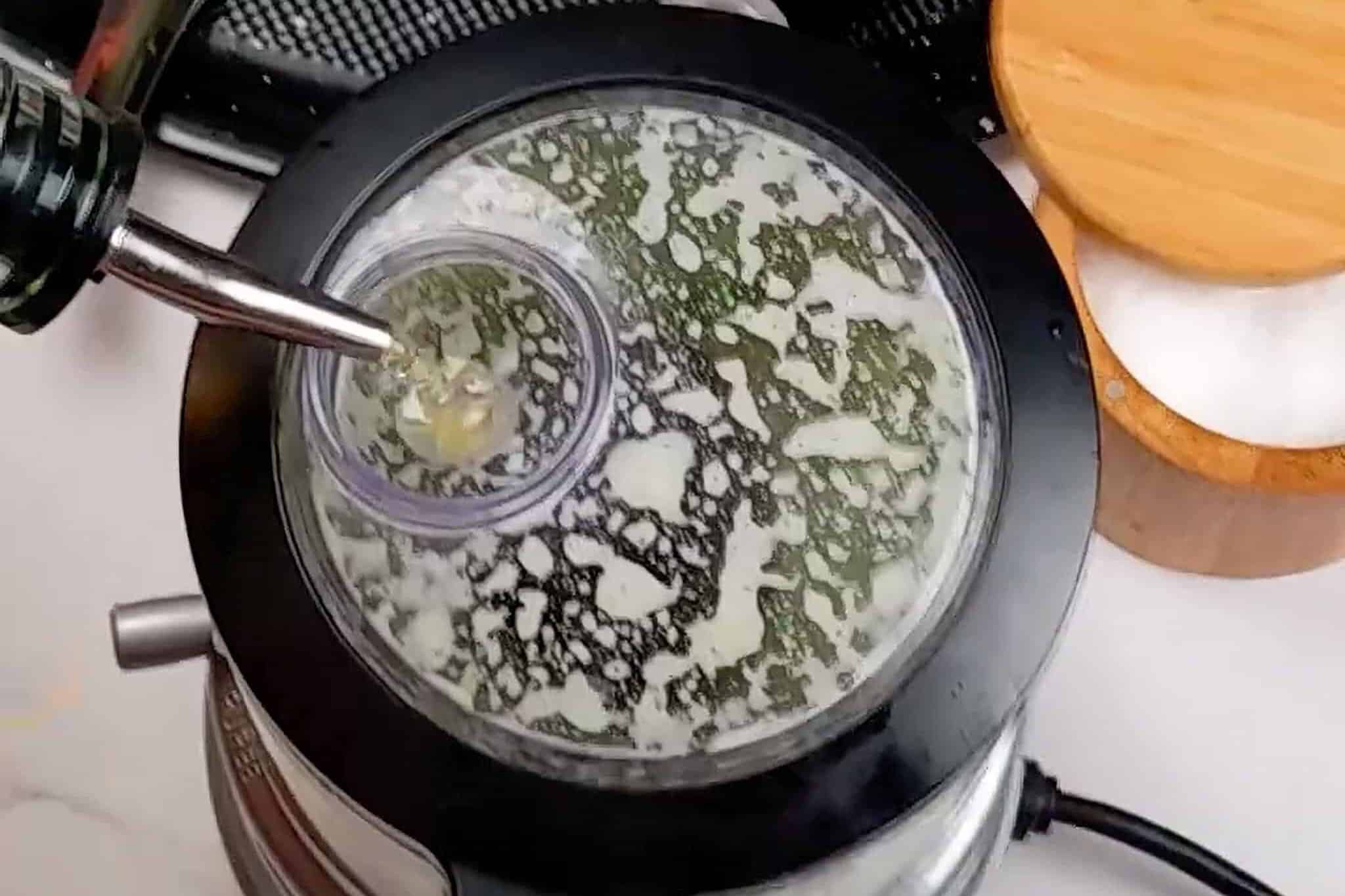 drizzling oil into the drizzle basin of the kitchenaid food chopper while blending cilantro, jalapeños, and lime for sauce for hte cilantro jalepeno sauce.