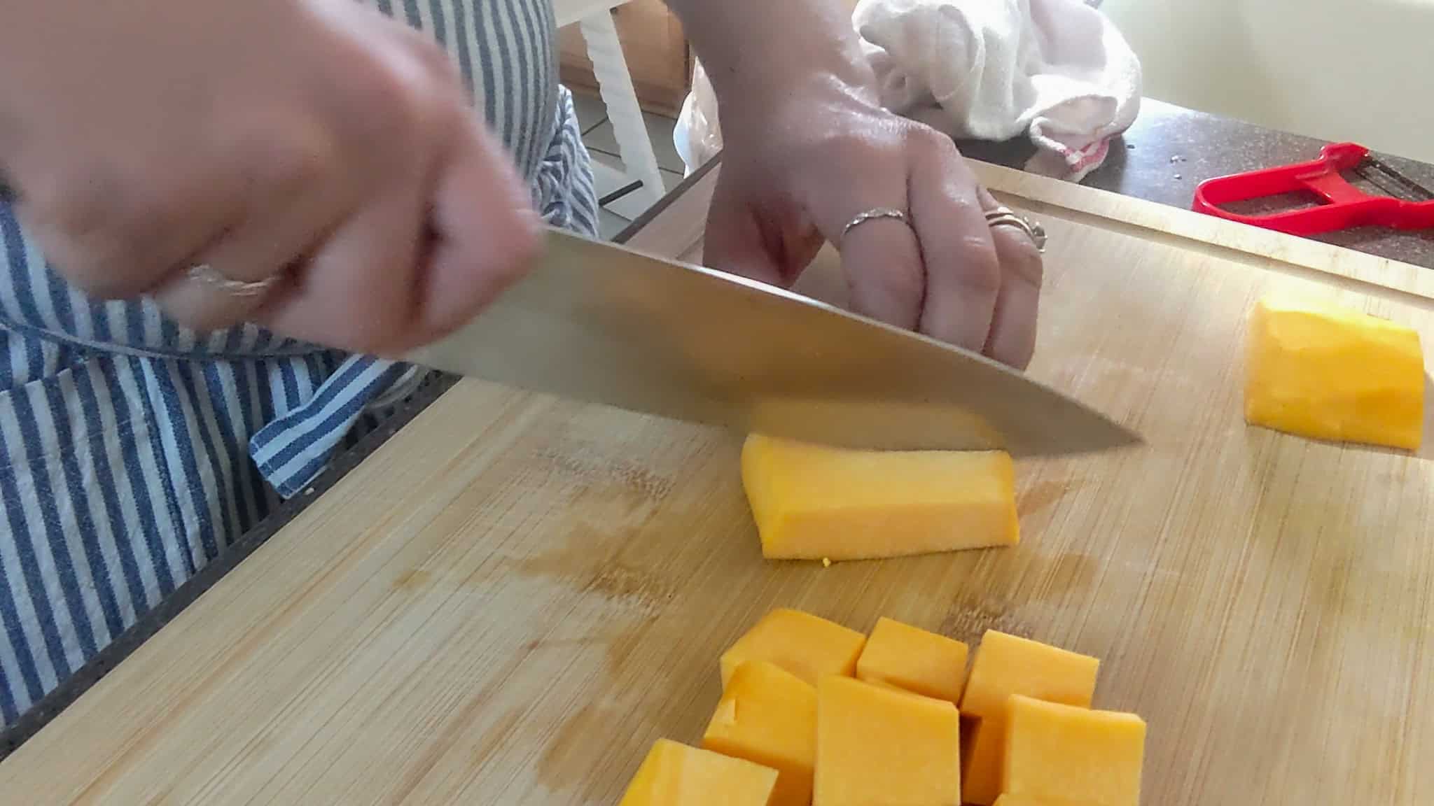 Chef Maika chopping butternut squash on a wooden cutting board for homemade baby food.