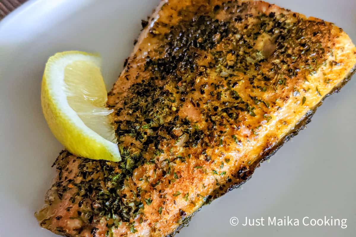 roasted trout fillet on a flat plate topped with a lemon wedge.