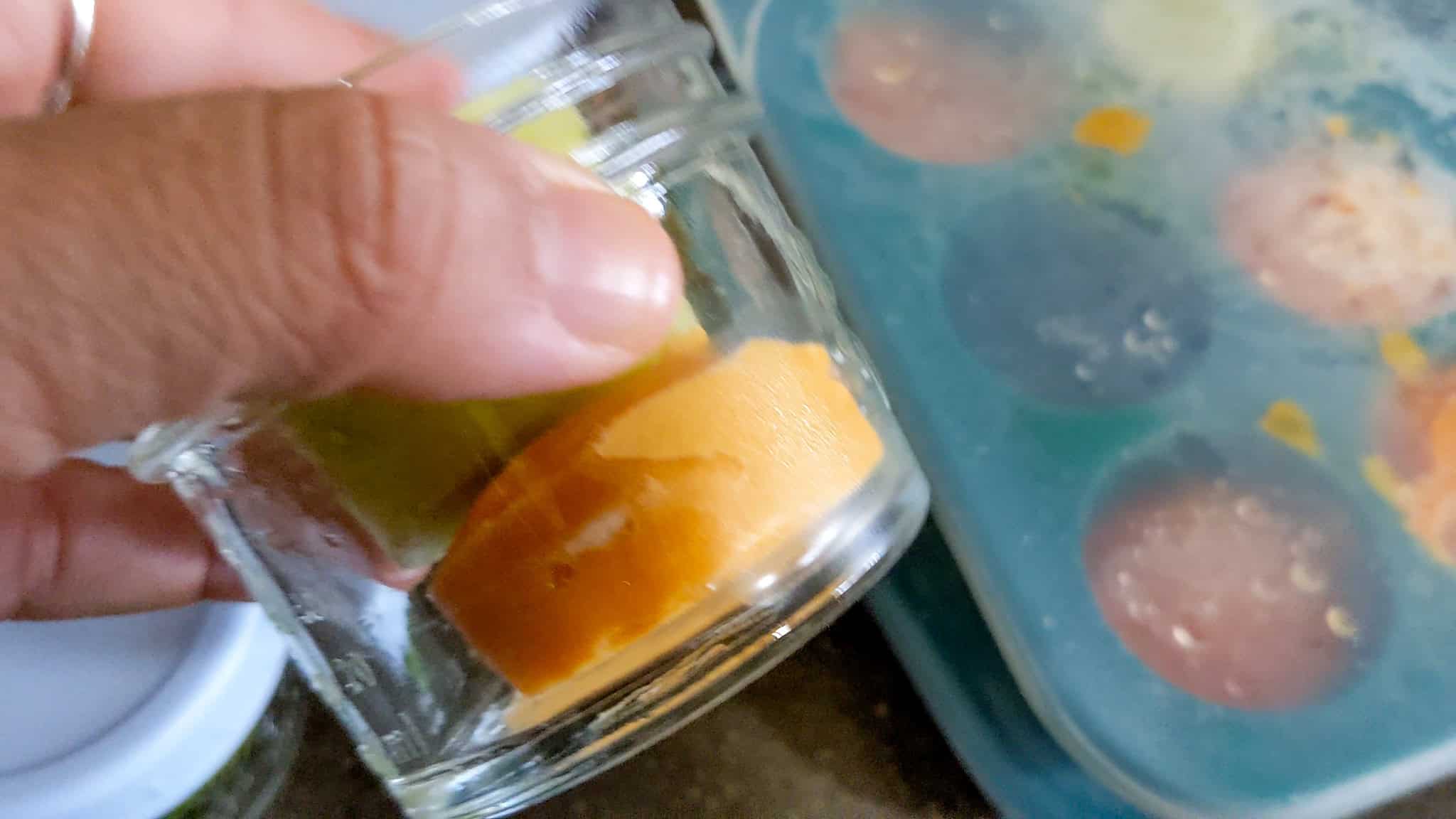 frozen homemade sweet potato and broccoli puree in a glass baby food jar.