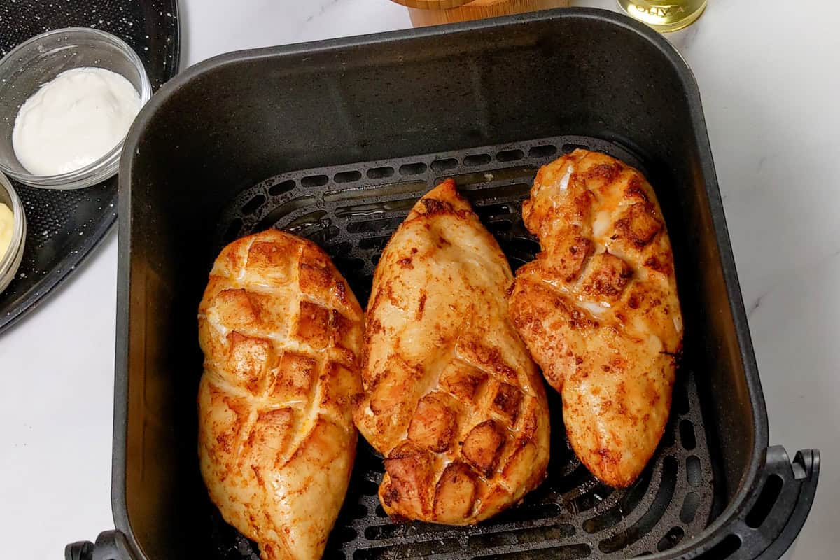 golden brown cooked air fryer diamond slit chicken breast in a cosori air fryer basket.