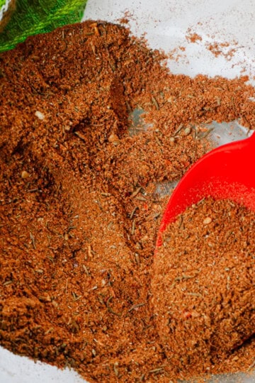golden redish hue of ras el hanout seasoning blend with a red GIR spoon.