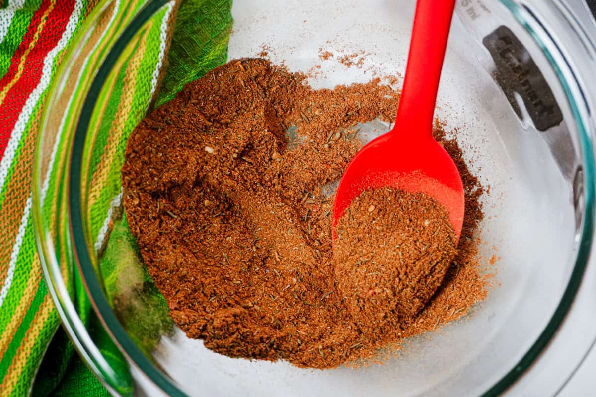 golden redish hue of ras el hanout seasoning blend with a red GIR spoon.
