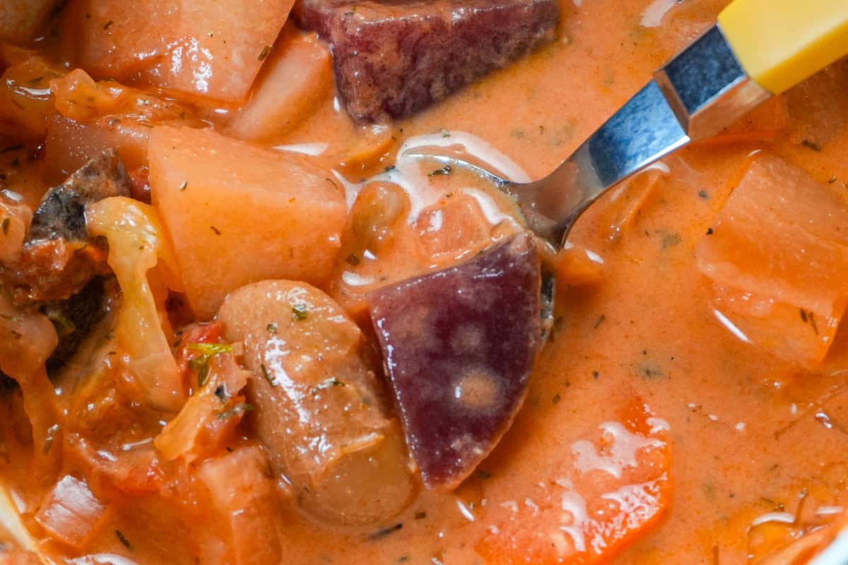 close up of a creamy borscht recipe with pre-cooked beets, cabbage, potatoes, and white beans in a hearty chicken-and-tomato broth.