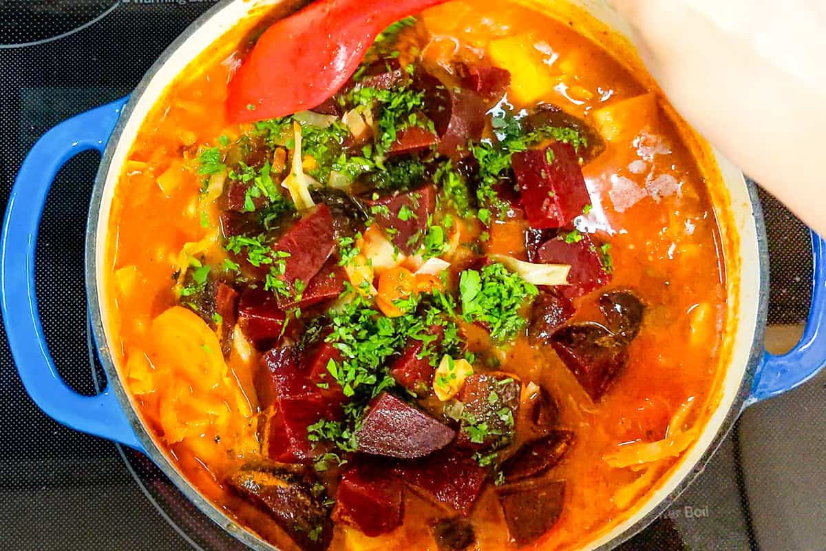 Pre-cooked diced beets added to a Dutch oven of hearty vegetable soup.