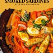 Smoked sardines with harissa, spinach, red bell peppers, tomatoes, and boiled eggs in a skillet with a title that says Easy Harissa Smoked Sardines with Spinach and Egg.