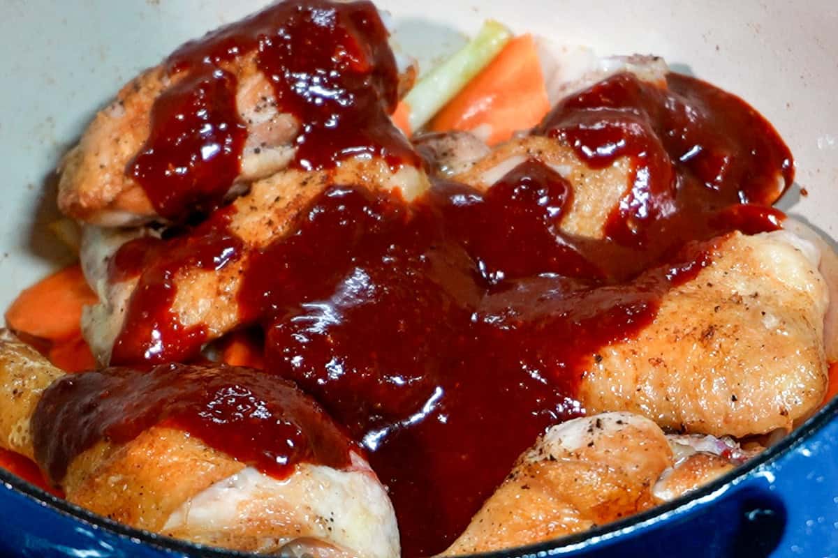 seared chicken with korean inspired sauce poured on top in a dutch oven.
