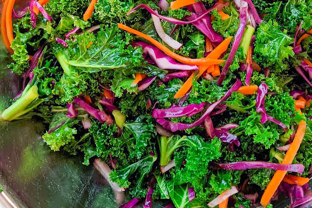 close up of massaged kale with strips of carrots, red radish and purple cabbage.