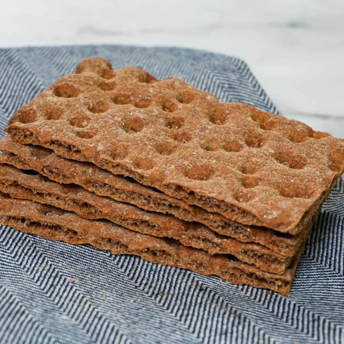wasa whole grain crispbread stacked on a clean folded kitchen towel placed on a counter.