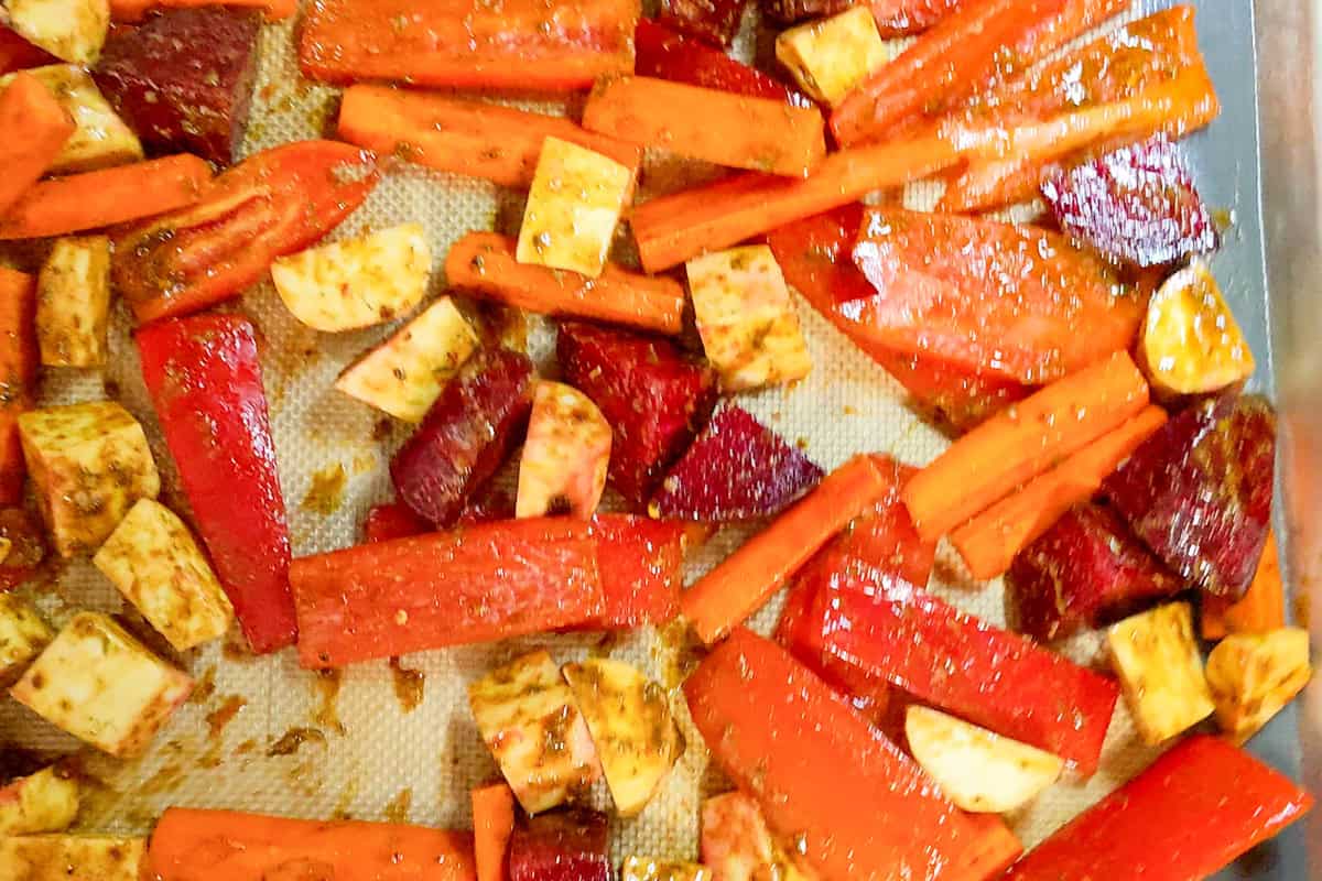 Mixed root vegetables tossed with ras el hanout and avocado oil on a sheet pan.